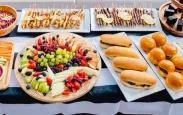 The yacht's table is filled with all kinds of food, fruits, breads, grilled meats, snacks