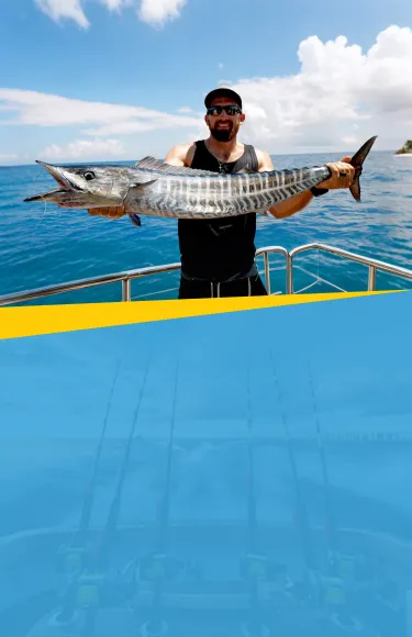 Tourists rentaing a yacht for a fishing trip in Dubai hold up a large fish they have just caught
